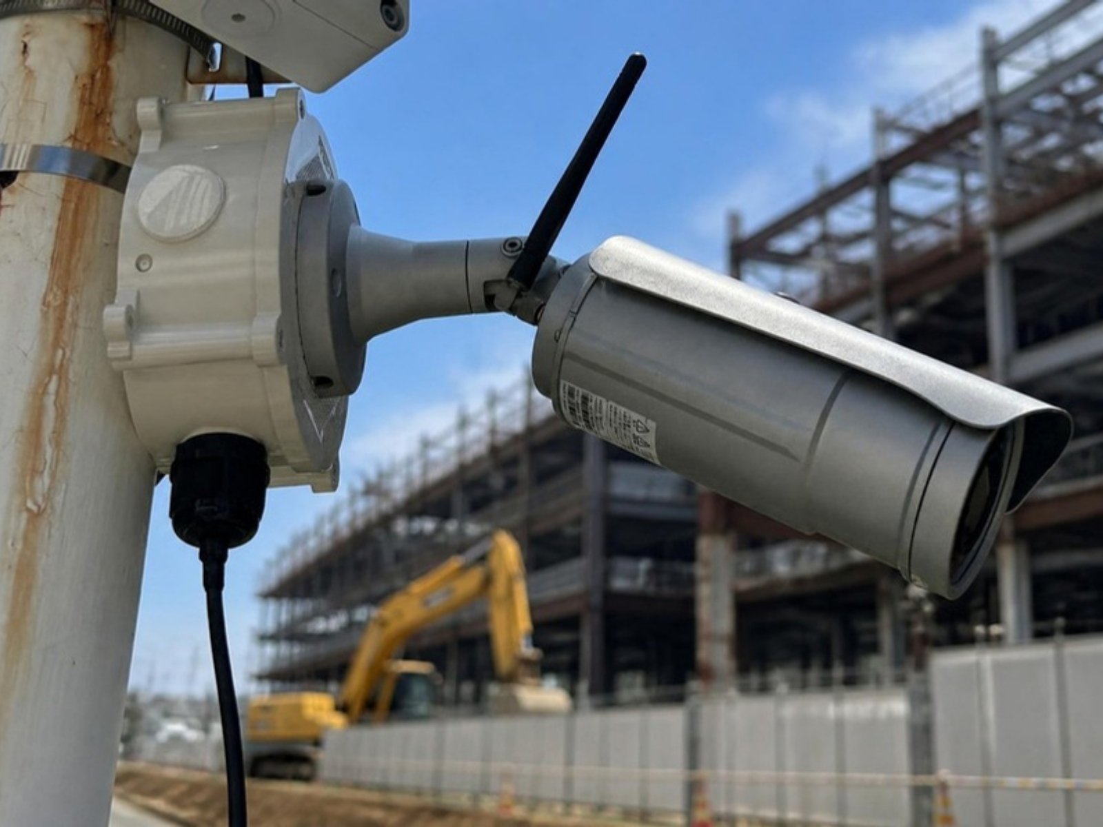 ポールに取り付けたアンテナ付きのLTEカメラ（実機）と、工事現場